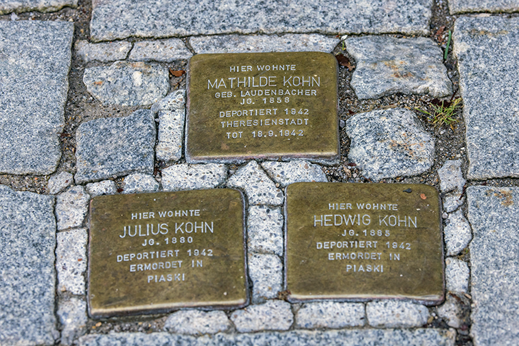 Bilder der drei Stolpersteinen mit folgendem Text: Auf dem ersten Stein steht: Hier wohnte Mathilde Kohn gebornene Laudenbacher Jahrgang 1858 deportiert 1942 nach Theresienstadt und gestoben 18.9.1942 Auf dem zweiten Stein steht: Hier wohnte Julius Kohn Jahrgang 1880 deportiert 1942 ermordet in Piaski Auf dem dritten Stein steht: Hier wohnte Hedwig Kohn Jahrgang 1885 deportiert 1942 ermordet in Piaski