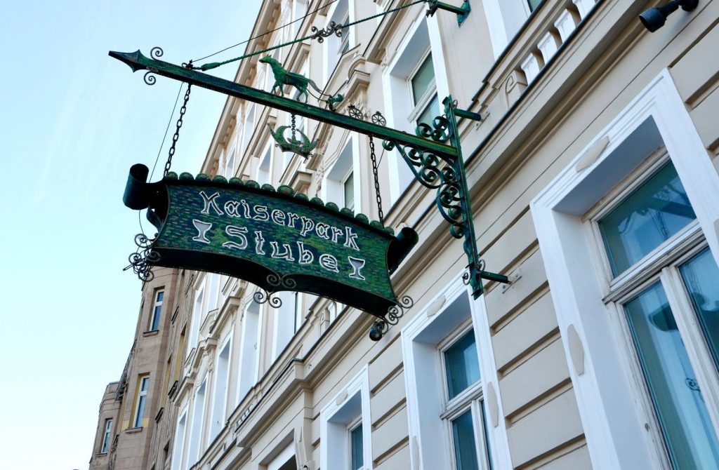 ein kunstvoll ausgearbeitetes grünes Eingangsschild, das an einer historischen Fassade angebracht ist